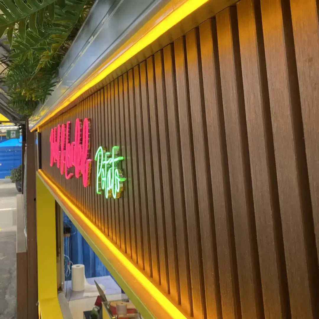 Wooden slat wall with yellow backlighting and neon signs showcasing Flex Neon for architectural applications