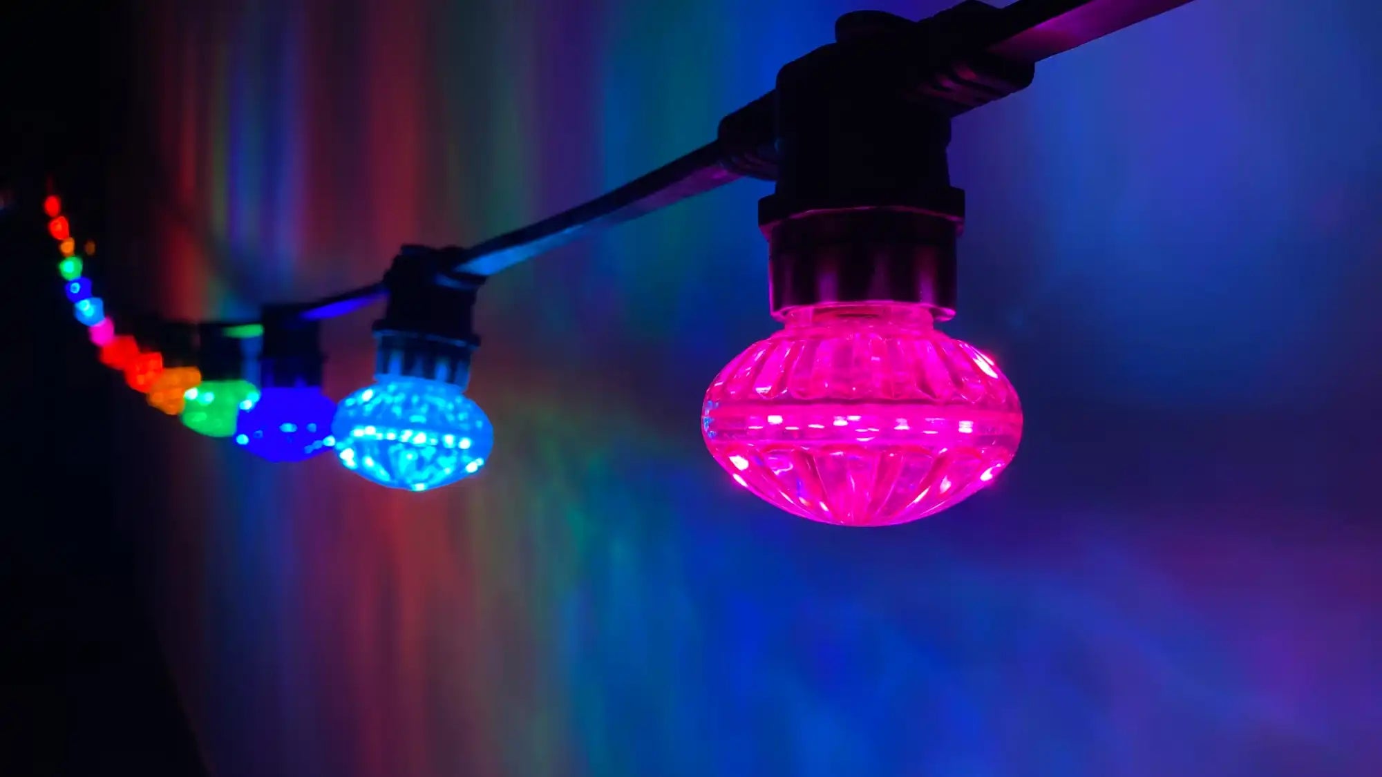 Colorful LED string lights with faceted bulbs glowing in pink and blue.