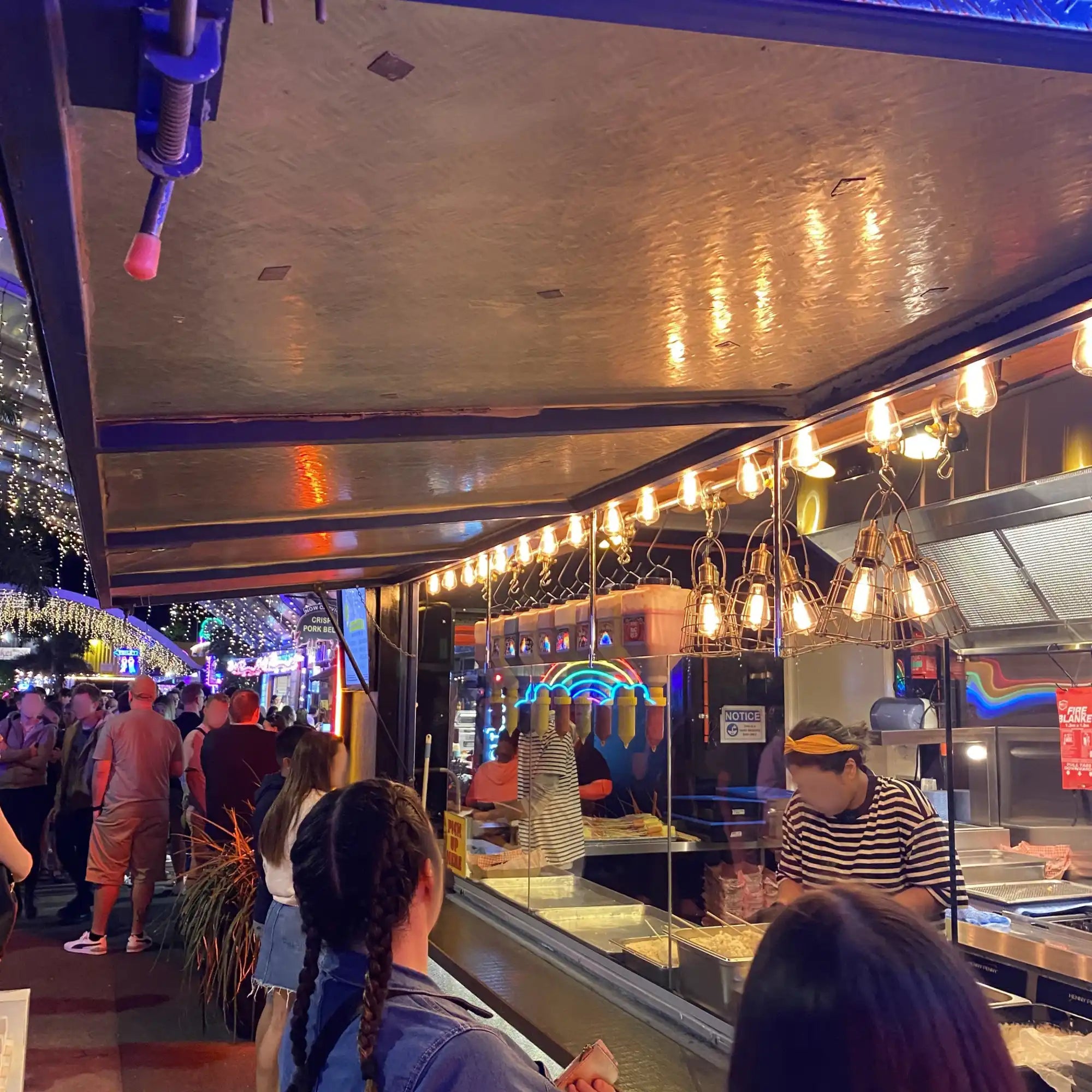 Food vendor stall with string lights and display cases.