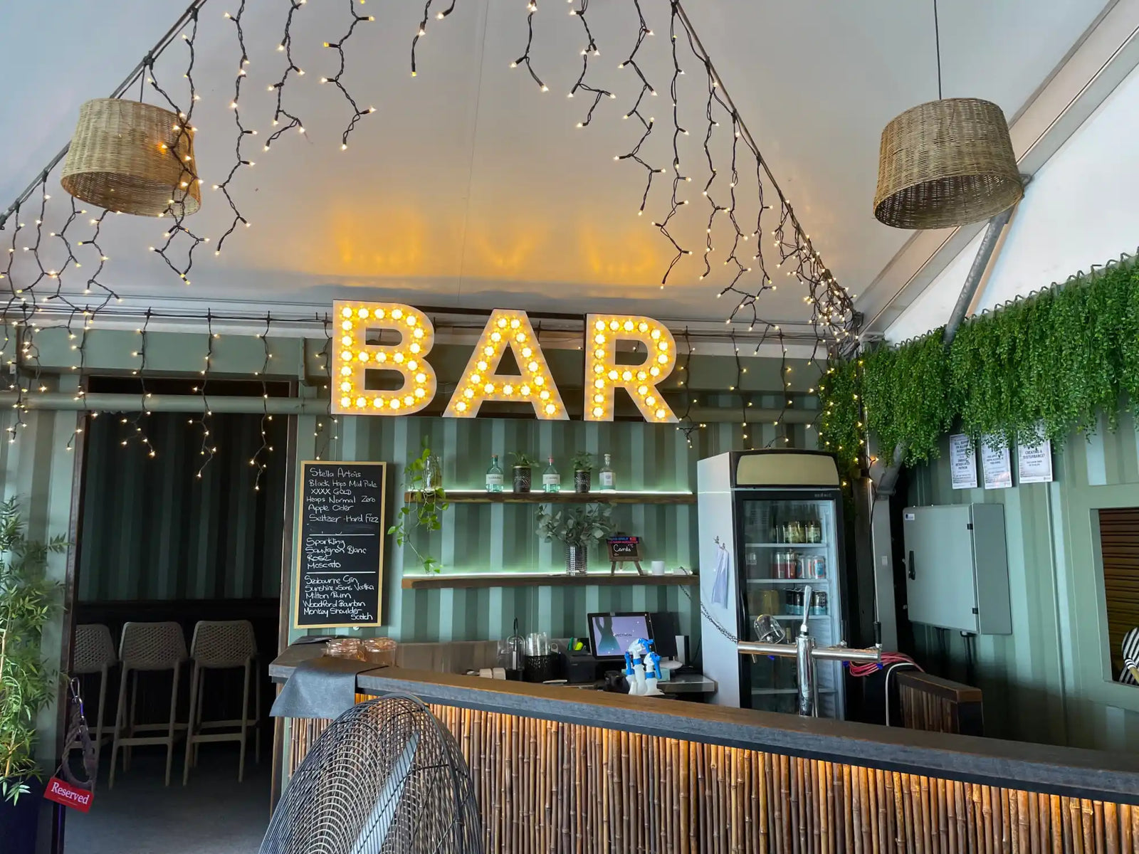 Illuminated ’BAR’ sign with glowing yellow marquee lights mounted above a counter.