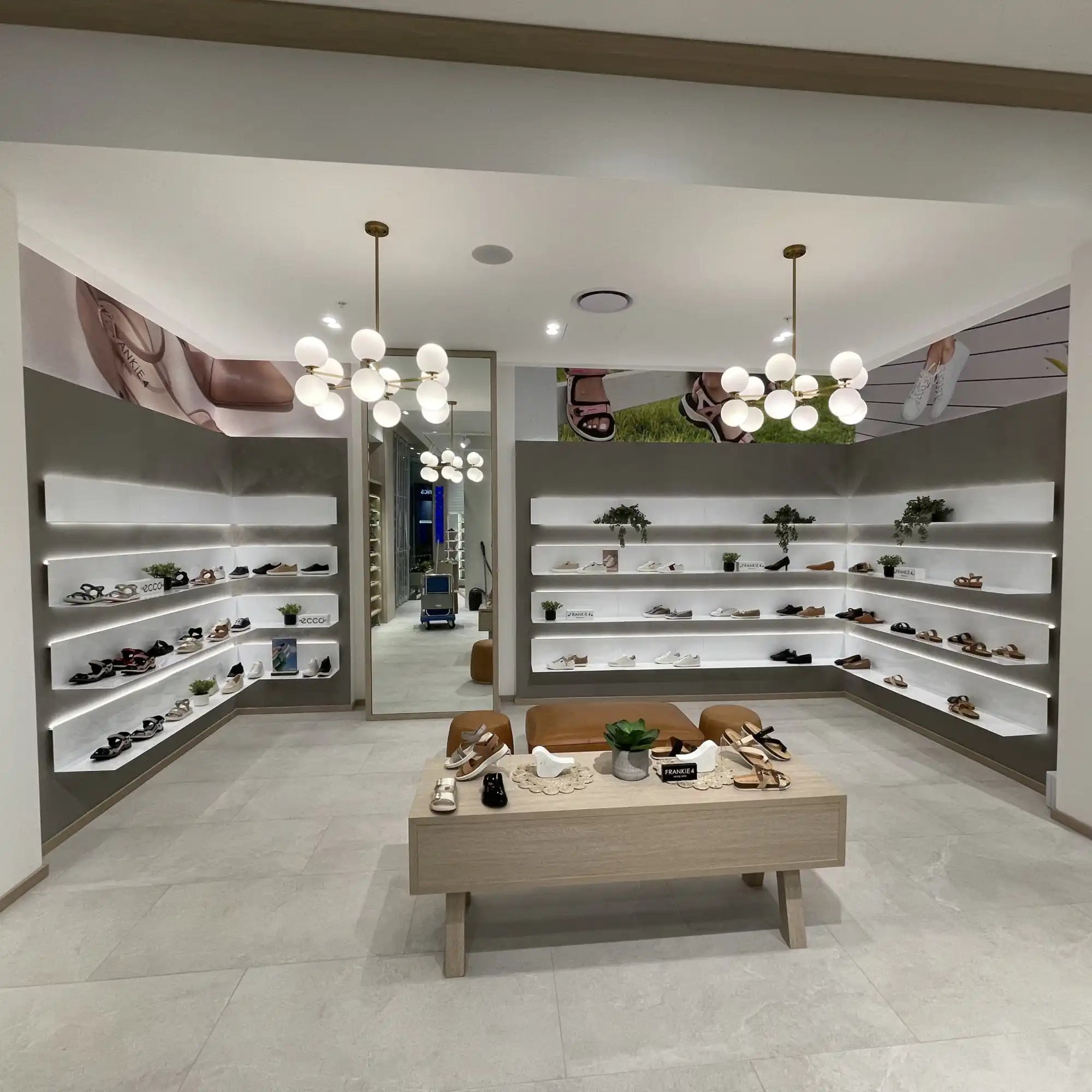 Modern shoe store display with floating wall shelves and a central bench table.