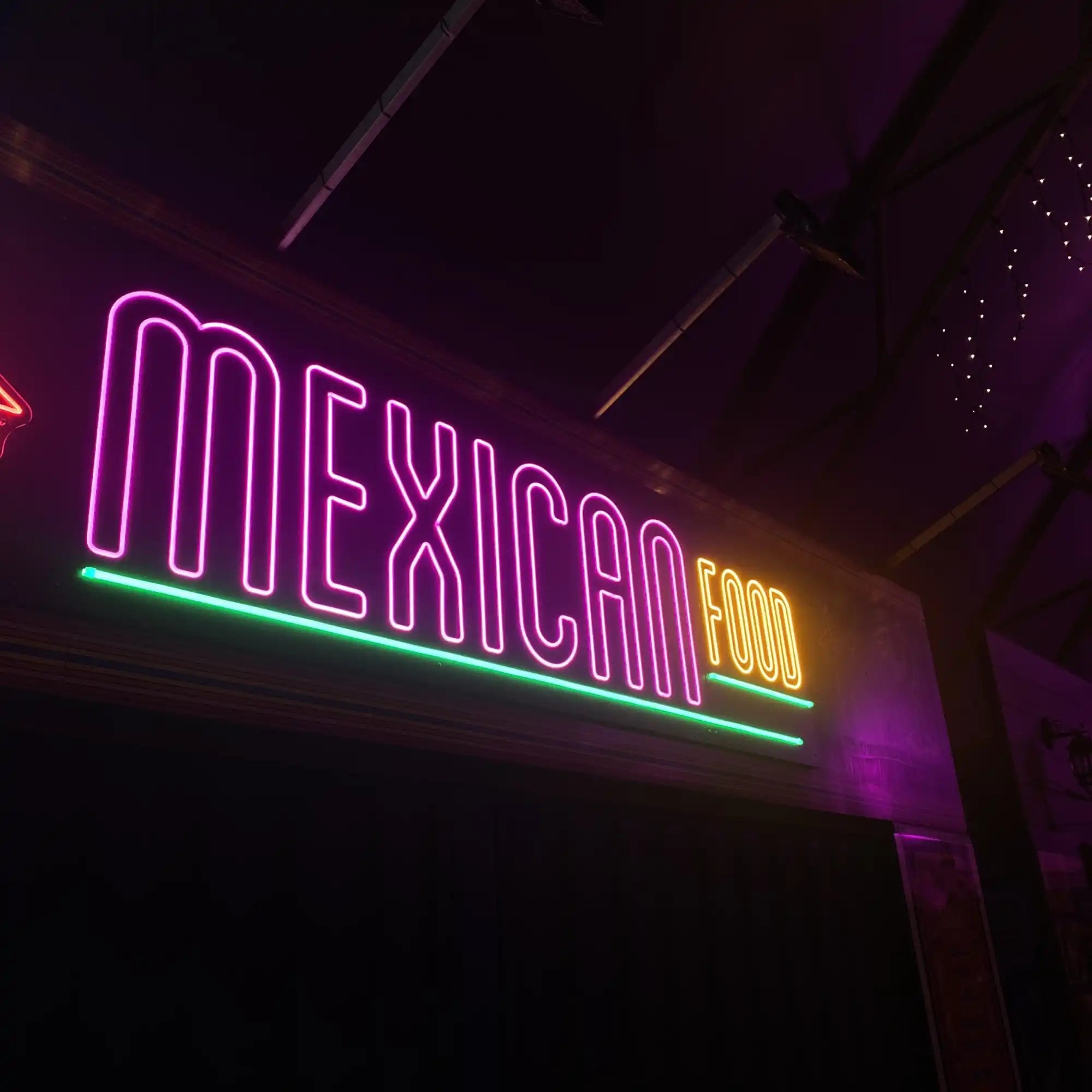 Neon sign displaying ’MEXICAN FOOD’ in pink and green lighting.